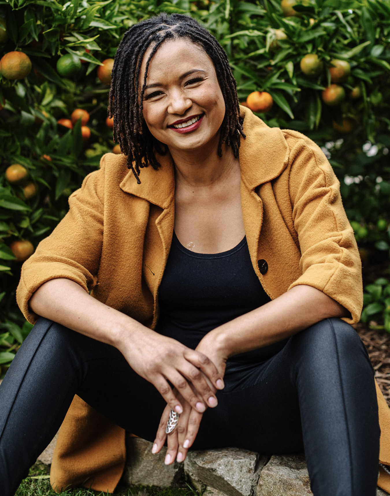 Solange Jacobs laughing in front of an orange tree
