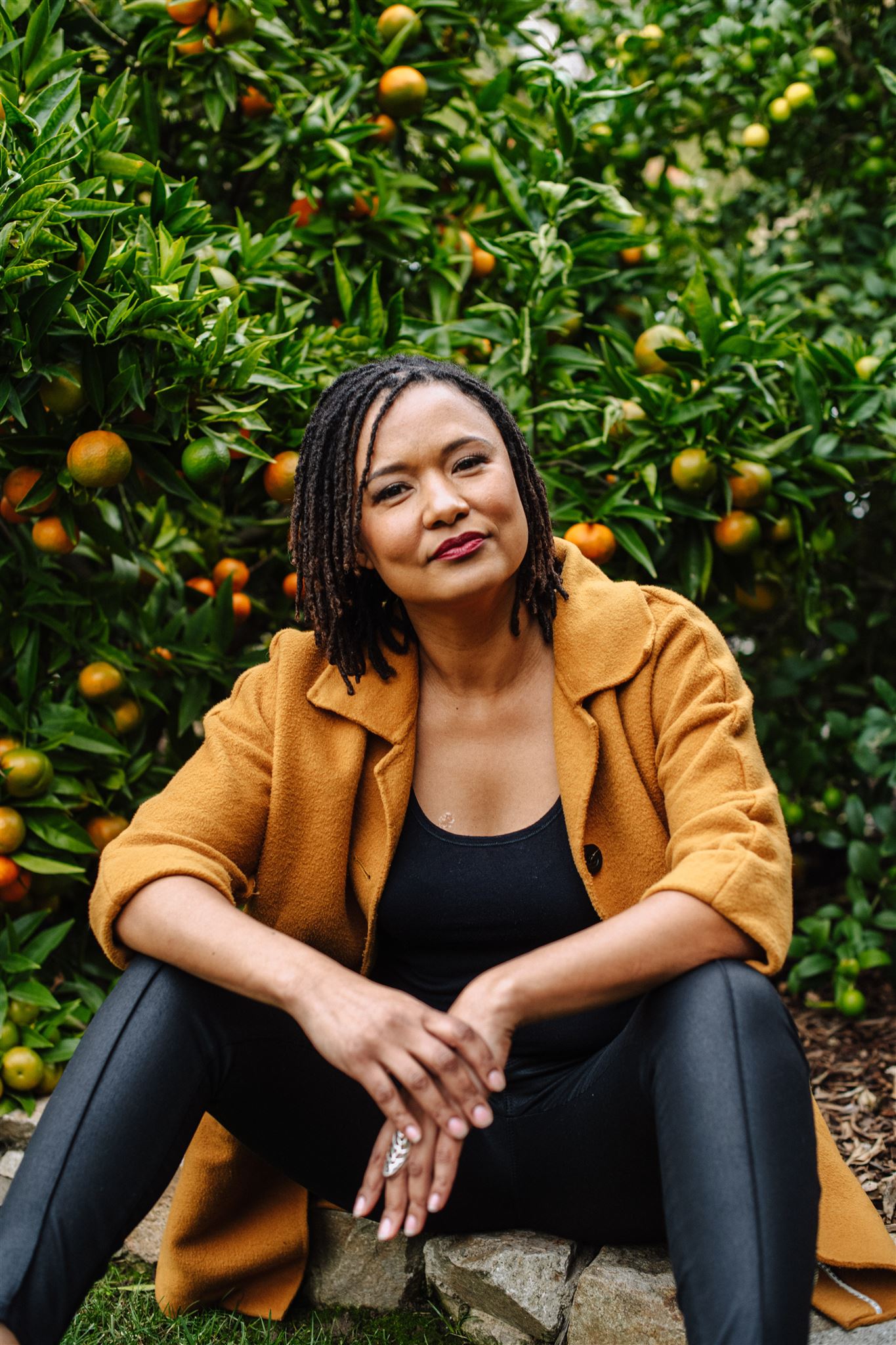 Solange Jacobs seated in front of an orange tree
